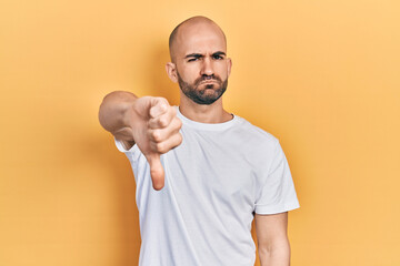 Sticker - Young bald man wearing casual white t shirt looking unhappy and angry showing rejection and negative with thumbs down gesture. bad expression.