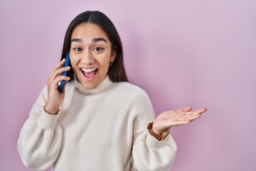 Young south asian woman having conversation talking on the smartphone celebrating achievement with happy smile and winner expression with raised hand