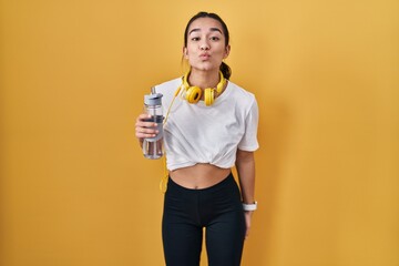 Poster - Young south asian woman wearing sportswear drinking water looking at the camera blowing a kiss on air being lovely and sexy. love expression.