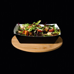 Ashes Classic Salad served in a box isolated on wooden board side view on black background fast food