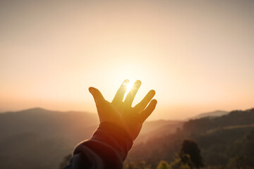 Wall Mural - Young man hand reaching for the mountains during sunset and beautiful landscape