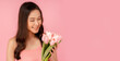 © Nutlegal - Portrait attractive asian women holding flowers or tulip flower Beautiful girl looking at flower with smile face Copy space isolated over pink pastel color background International Women's Day