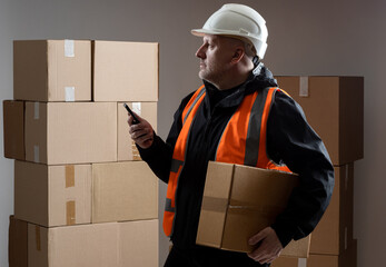 Poster - Customs registration. A man with a scanner in a warehouse. The man works at customs. The employee uses the barcode scanner. Passing goods across the border. A customs officer registers postal goods.