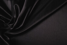 Abstract Monochrome Elegant Luxury Cloth Background. Black Color Background With Drapery And Wavy Folds Of Luxurious Silk Satin Material. Top View