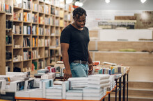 African American Man Picking And Reading Books In Library Or Bookstore