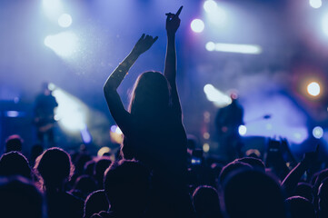 Wall Mural - Silhouette of a woman with raised hands on a concert