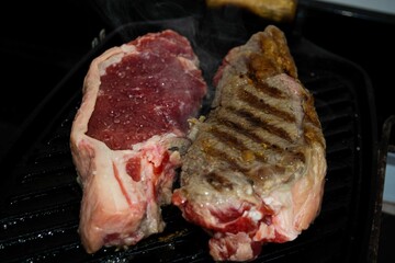 Sticker - Closeup shot of two sirloin steak pieces on a grill with one side seared and the other raw