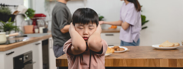 domestic violence. Stressed Asian kid covering his face after mom and dad started arguing.