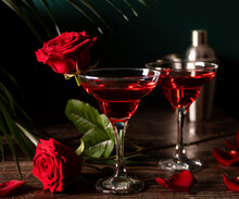 Delicious Refreshing Beverage Drink Red Cocktail With Red Rose And Petals On Wooden Table. Romantic, Valentines Day Concept.
