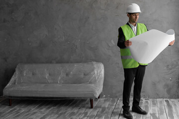 Muslim engineering businessman hold paper blueprint and helmet white check gypsum board wall interior decoration of home in construction site, architecture and home renovation