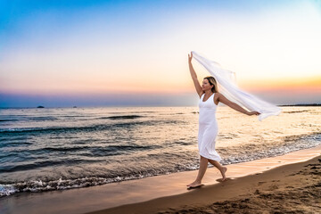 Wall Mural - Woman walking on beach at sunset
