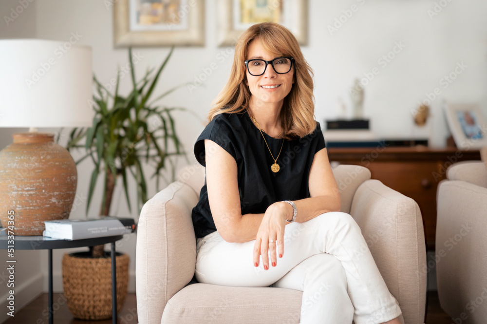 Portrait of smiling mature woman relaxing in an armchair at home Stock ...