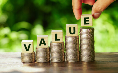 Wooden cubes with value word on stacked of coins in stair shape on nature background.             