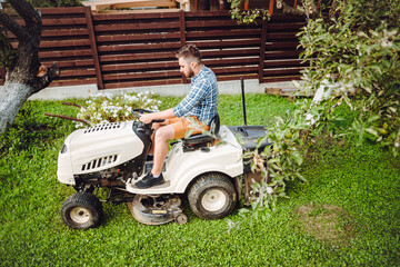 Wall Mural - Portrait of worker using lawn mower tractor .