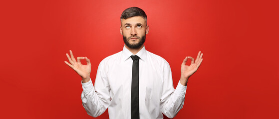 Wall Mural - Handsome meditating businessman on red background