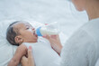 baby consumes milk from  bottle fed by mother