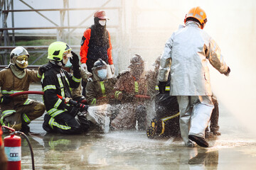 Firefighters using Twirl water fog type fire extinguisher to fighting with the fire flame from oil to control fire not to spreading out. Firefighter and industrial safety concept.