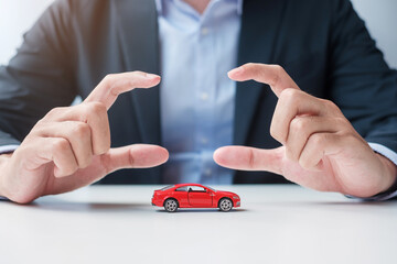 Wall Mural - Businessman hand cover or protection red car toy on table. Car insurance, warranty, repair, Financial, banking and money concept