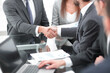 © ASDF - Two businessmen shaking hands with colleagues on background.