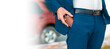 © _KUBE_ - A businessman in a blue suit get a leather key bag from the pants. Banner with copy space. Close-up of the hands. The concept of style and fashion