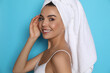 © New Africa - Beautiful young woman with towel on head against light blue background