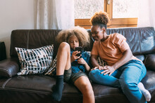Boy Using Smart Phone Sitting With Mother On Sofa At Home
