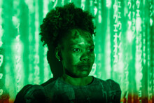 Digital Code Falling On Woman With Afro Hairstyle In Front Of Wall