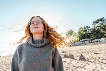 Young Woman With Eyes Closed Enjoying Fresh Air At Beach