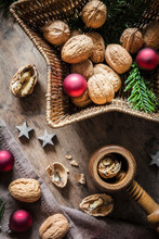 Studio Shot Of Cutting Board, Star Shaped Wicker Basket, Christmas Ornaments, Walnuts And Simple Nutcracker