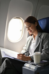 Gorgeous businesswoman reading a meeting proposal report during flight.