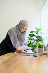 Wall Mural - Professional muslim businesswoman or accountant wearing hijab, holding a financial report