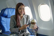 © Jirapong - Portrait of a young Asian businesswoman smiling while riding a plane