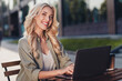 © deagreez - Portrait of attractive cheerful wavy haired girl copywriter using netbook studying remotely in complex outdoors