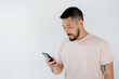 © LIGHTFIELD STUDIOS - bearded asian man with tattoos using smartphone isolated on grey.