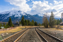 Railroad Track On Countryside Rural Area. Snow Capped Mountains Over Blue Sky White Clouds. Canadian Rockies Jasper National Park Whistlers Peak.