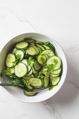 Wall Mural - Fresh cucumber salad with cilantro and oil in white bowl.