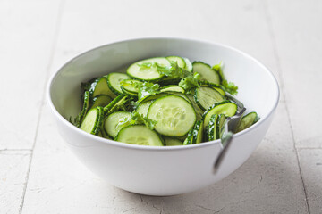 Canvas Print - Fresh cucumber salad with cilantro and oil in white bowl.