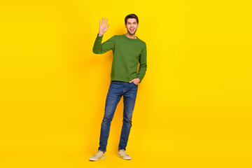 Photo of sweet attractive guy dressed green pullover smiling waving arm isolated yellow color background