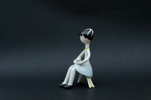Vintage Porcelain Figurine - Girl Sitting On A Chair And Holding A Cat Isolated On Black Background
