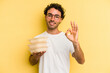 © Asier - Young caucasian man holding tupper isolated on yellow background cheerful and confident showing ok gesture.
