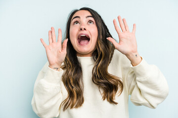 Wall Mural - Young caucasian woman isolated on blue background screaming to the sky, looking up, frustrated.