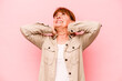 © Asier - Middle age caucasian woman isolated on pink background feeling confident, with hands behind the head.