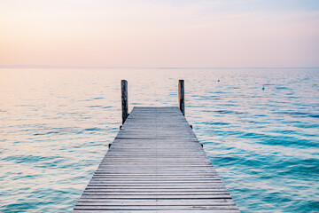 Wall Mural - Wooden jetty pier on the sea at sunrise. Beautiful summer landscape in Italy