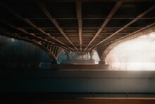 Beautiful shot under a huge old steel bridge with bright light and trees in the background
