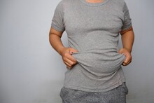 Man In Gray T-shirt Holding And Lifting His Fat Flabby Belly