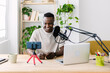© Xavier Lorenzo - Young adult african man streaming live video at home studio - Millennial content creator male recording radio podcast - Entertainment and broadcasting concept