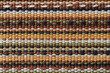 Plain weave fabric macro texture. Cloth background with horizontal strips of white, yellow, green, brown and black colors. Textile surface. Colorful woven fabric as design element. Weft and warp.