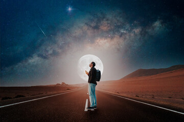 Wall Mural - person standing on the road in the desert with full moon and milky way background