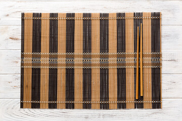 Wall Mural - Two chopsticks and bamboo mat on wooden background. Top view, copy space