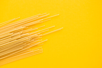 Spaghetti pasta on yellow background, from above